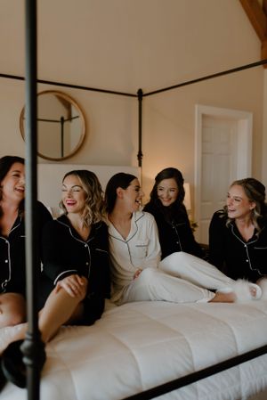 Group sharing joyful laughter while relaxing on a bed in matching loungewear.