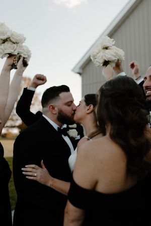 Wedding celebration moment with raised bouquets and cheering guests outdoors.