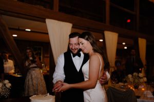 Intimate moment shared during wedding reception in rustic venue with ambient lighting.