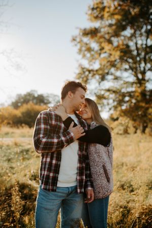 Couple sharing intimate moment in golden sunlight against autumn background.