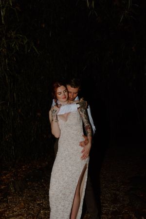 Intimate wedding couple embrace in dark outdoor setting.