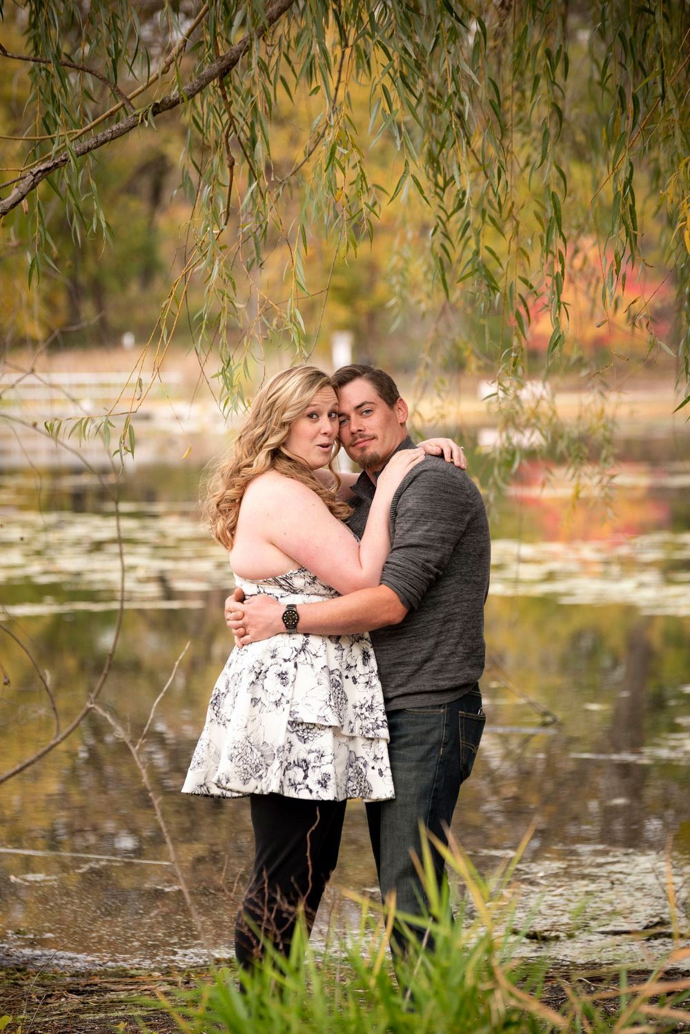 A romantic autumn photoshoot by a pond with willow branches hanging overhead.