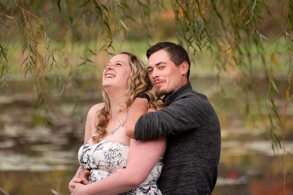 A tender embrace captured in a natural setting with autumn colors in the background.
