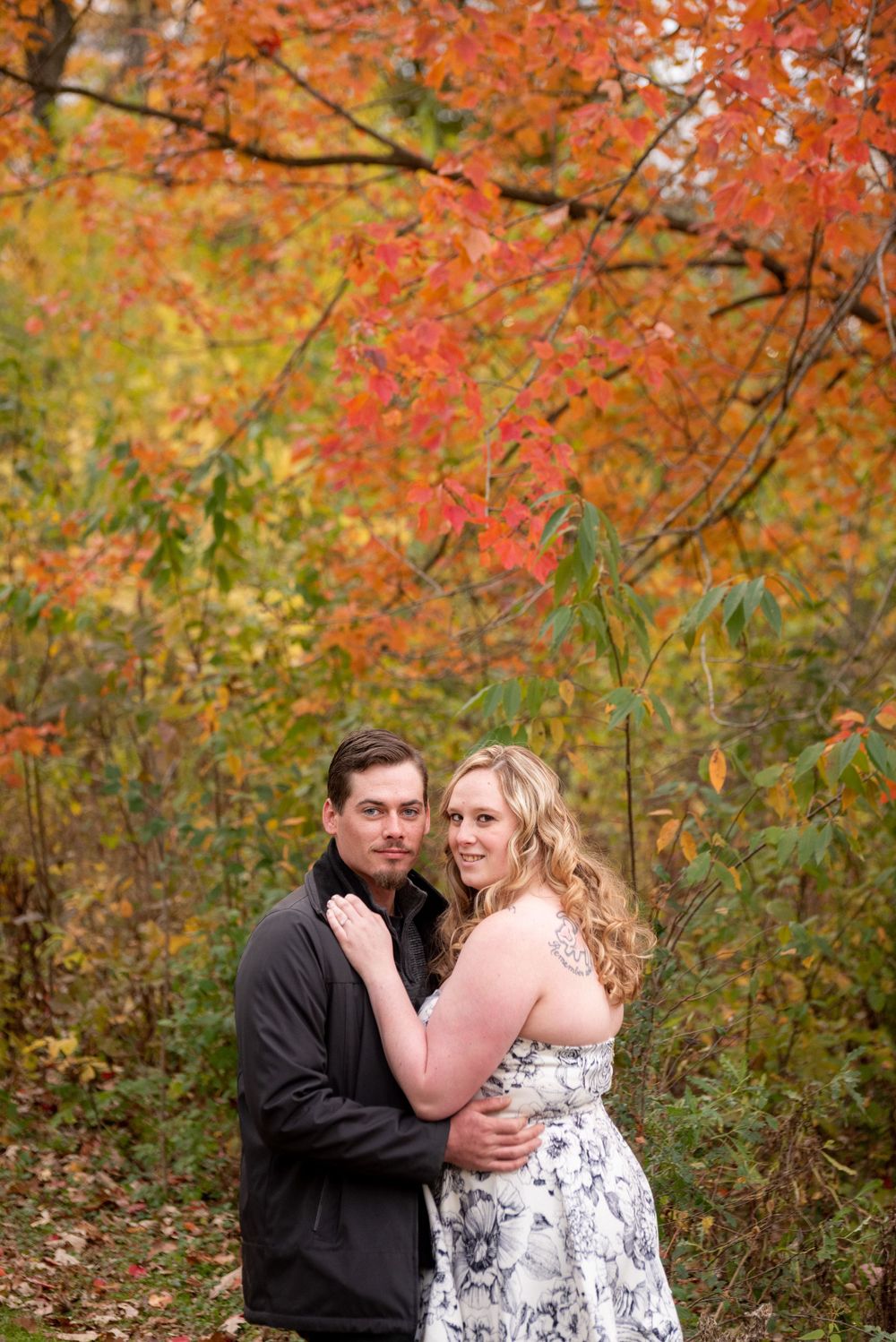 An intimate autumn photoshoot with bright orange maple leaves creating a colorful backdrop.