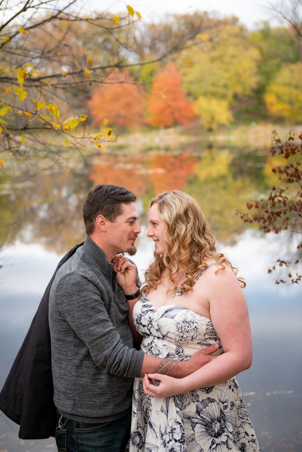 A lakeside autumn photoshoot with yellow and orange fall colors reflecting on the water.
