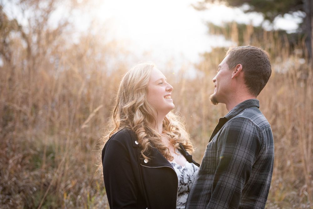 Romantic couple shares tender moments in tall grass during fall photoshoot.