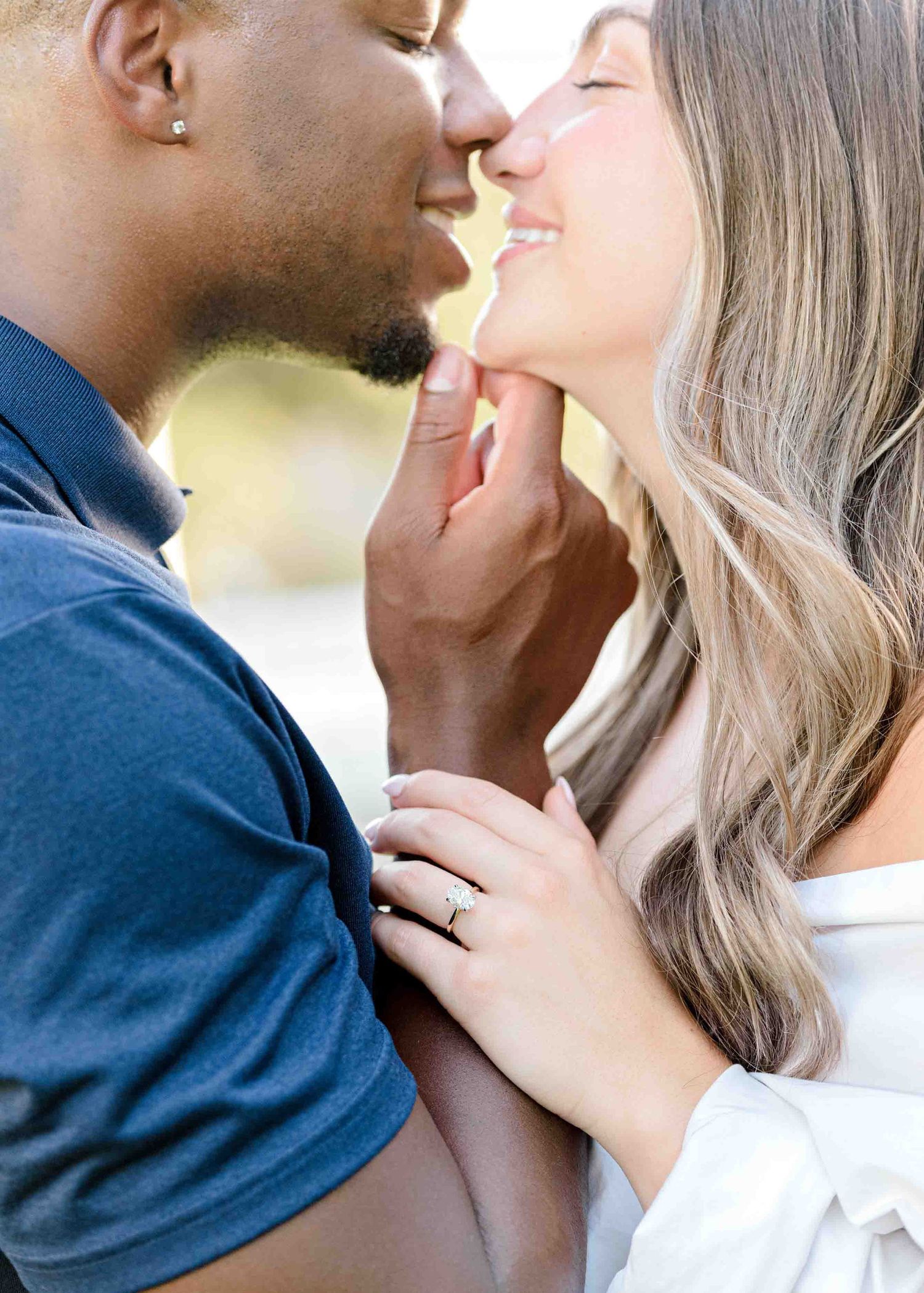 An intimate close-up photo of a couple sharing a tender moment outdoors.
