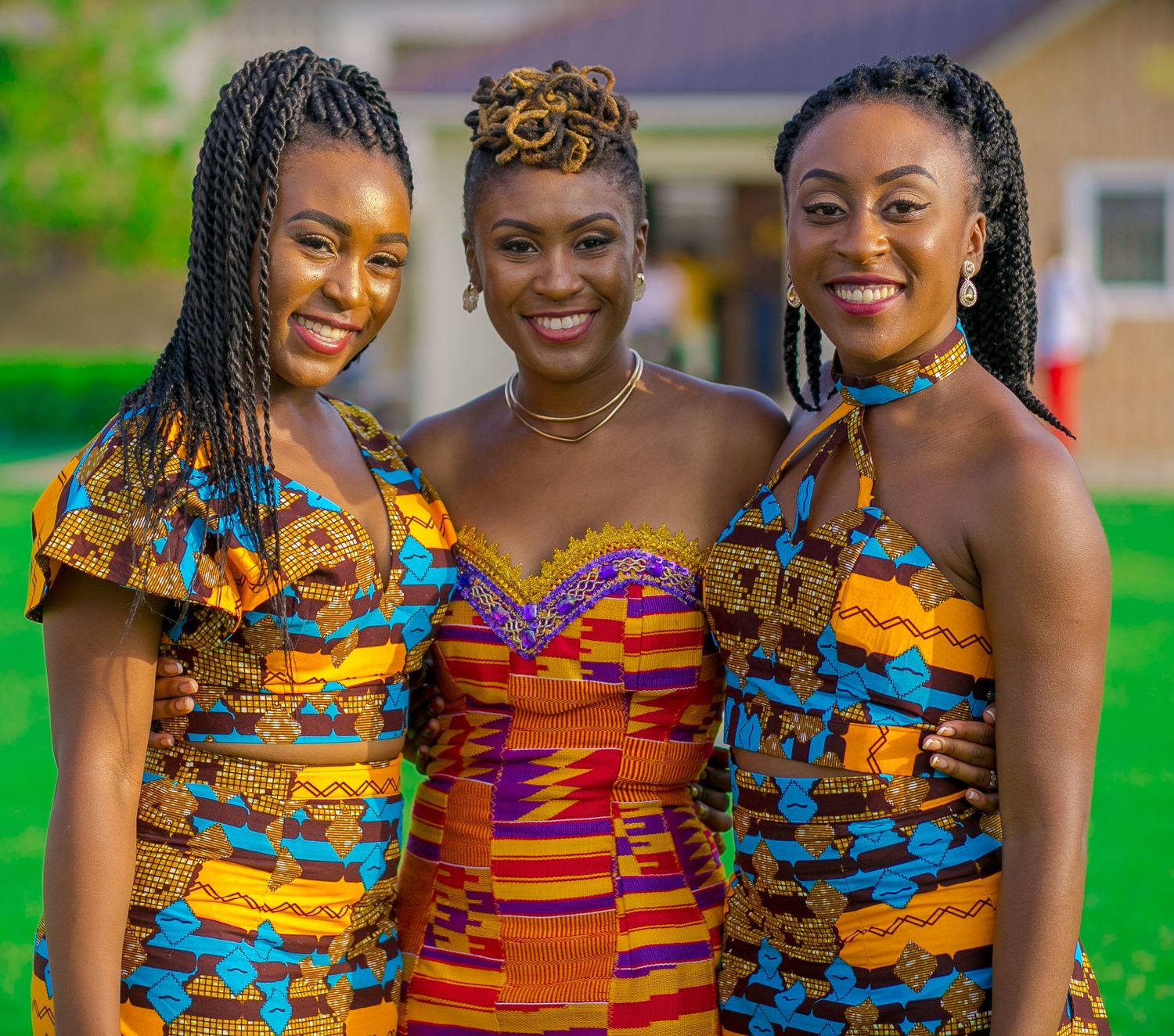 Group photo of people wearing vibrant African print dresses in orange and blue patterns.