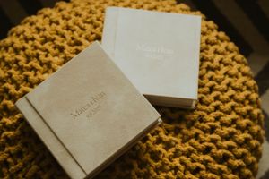 Two wedding album boxes positioned on yellow knitted surface.