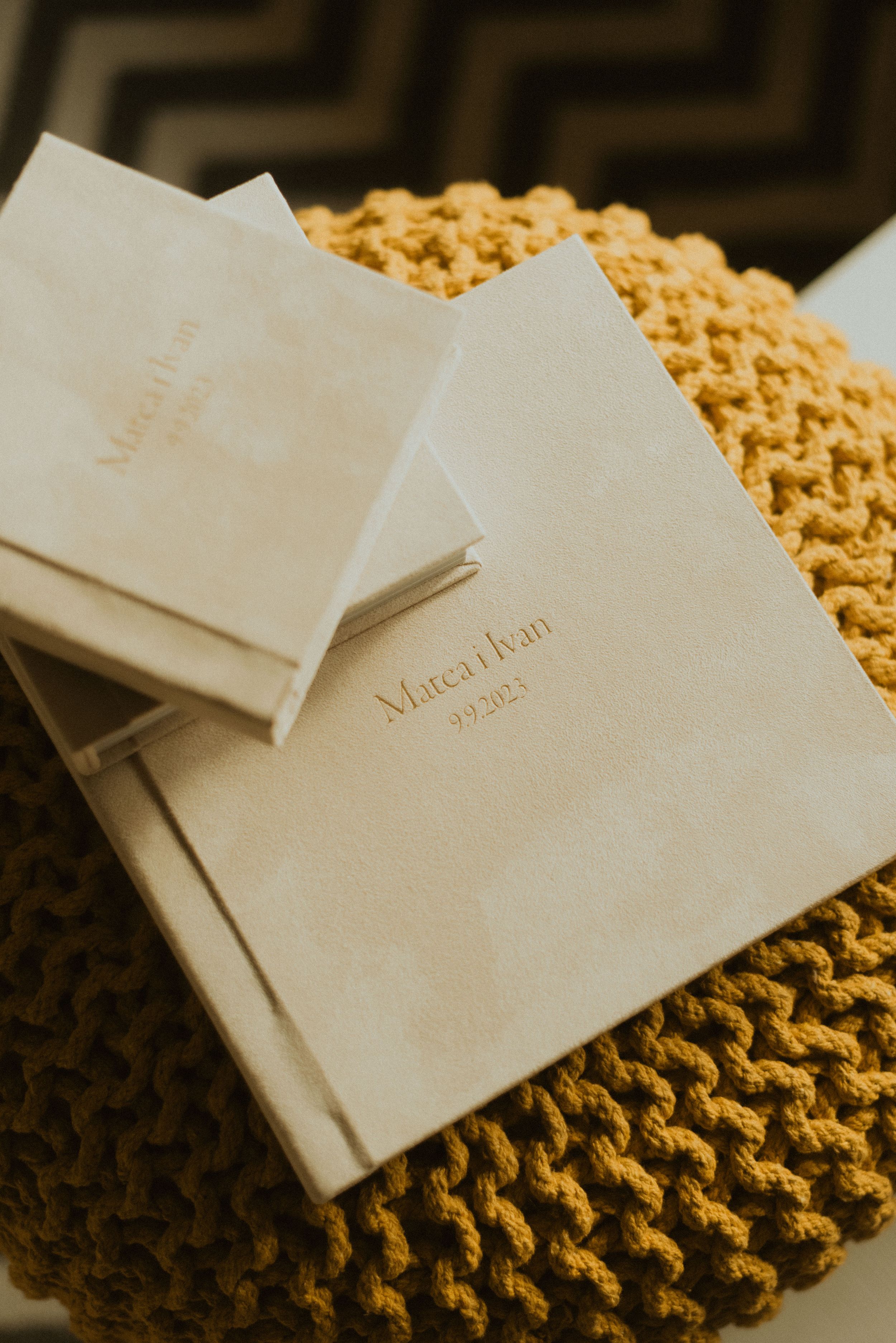 Multiple wedding albums with Mateo Bean branding stacked on yellow knit textile.