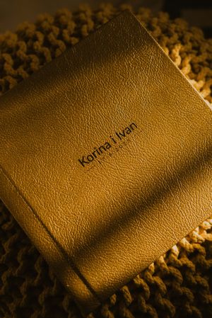 Brown leather photo album with text embossed on cover against knitted background.