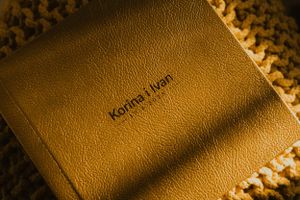 Close-up shot of a premium brown leather wedding album with textured surface illuminated by warm lighting.