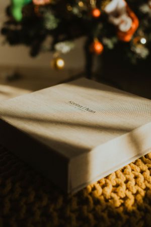 Wedding album resting on a textured surface with christmas lights bokeh in the background.