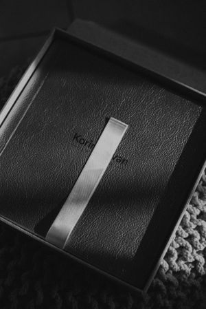 Sleek black leather photo album with silver metallic stripe detail shown in dramatic lighting.