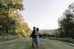 Couple embracing on scenic hilltop path surrounded by summer greenery.