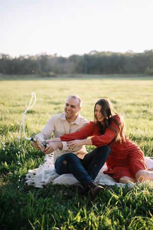 A couple enjoying a picnic in a sunlit meadow during golden hour.