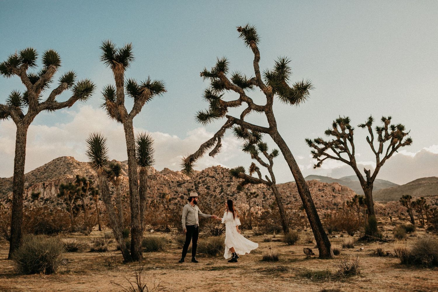 A romantic desert wedding photo shoot among towering Joshua Trees and mountains.