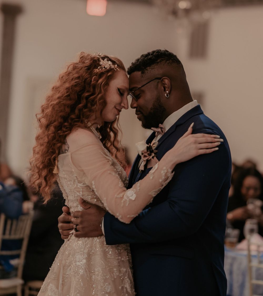 Couple sharing romantic dance moment at wedding reception in elegant attire.