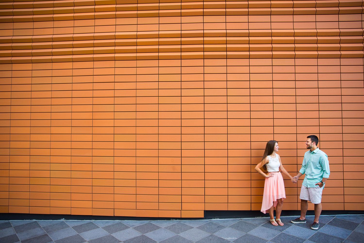 Couple converses against an orange-tinted geometric wall pattern.
