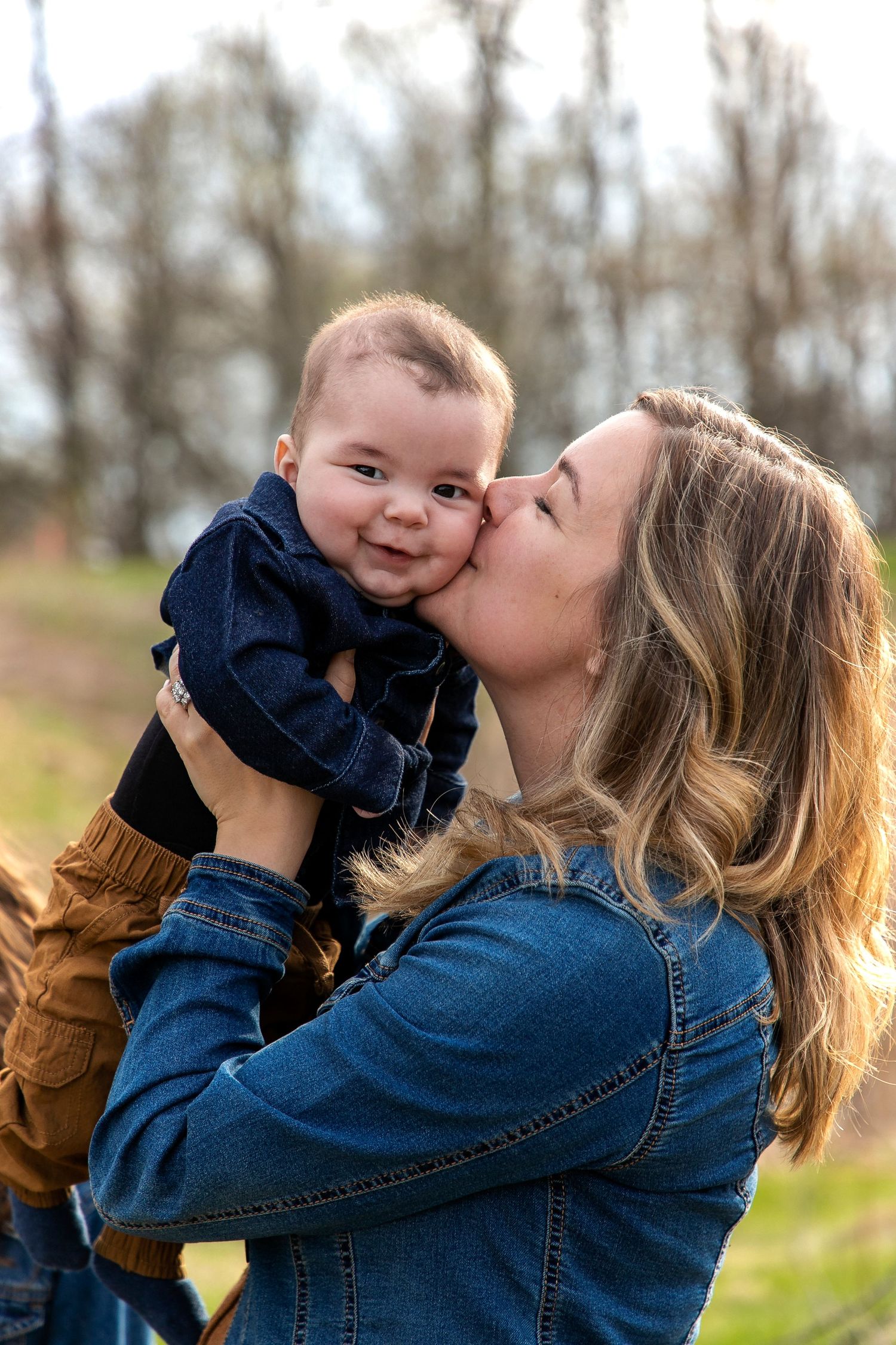 A mother holding her baby boy up in the air and kissing him on the cheek