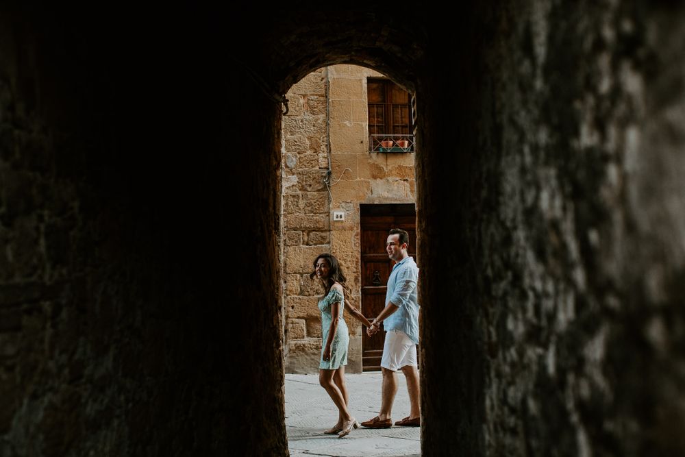 A couple seen through a stone archway in an ancient European building.
