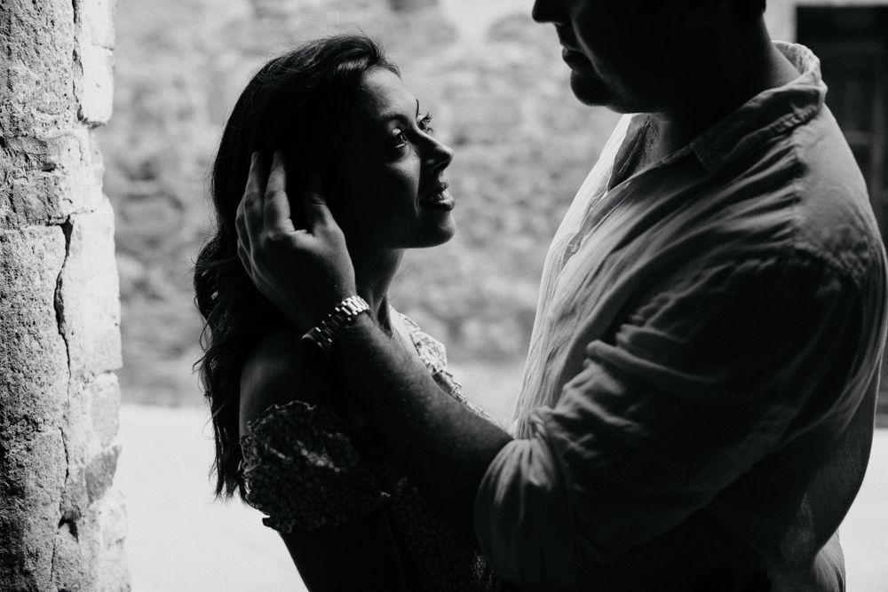 An intimate black and white portrait captured against a textured stone wall.