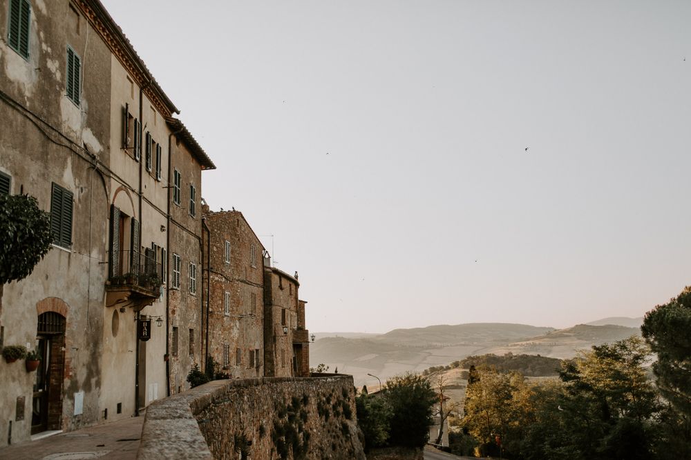 A scenic view of old Italian architecture and rolling hills in soft evening light.