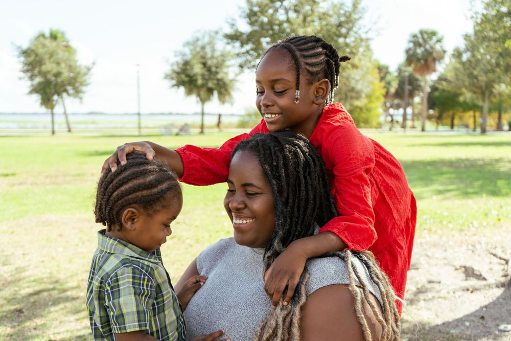 A sweet family moment captured outdoors in a park setting.
