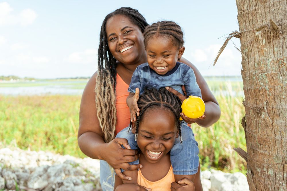 A loving family moment captured outdoors on a sunny day.