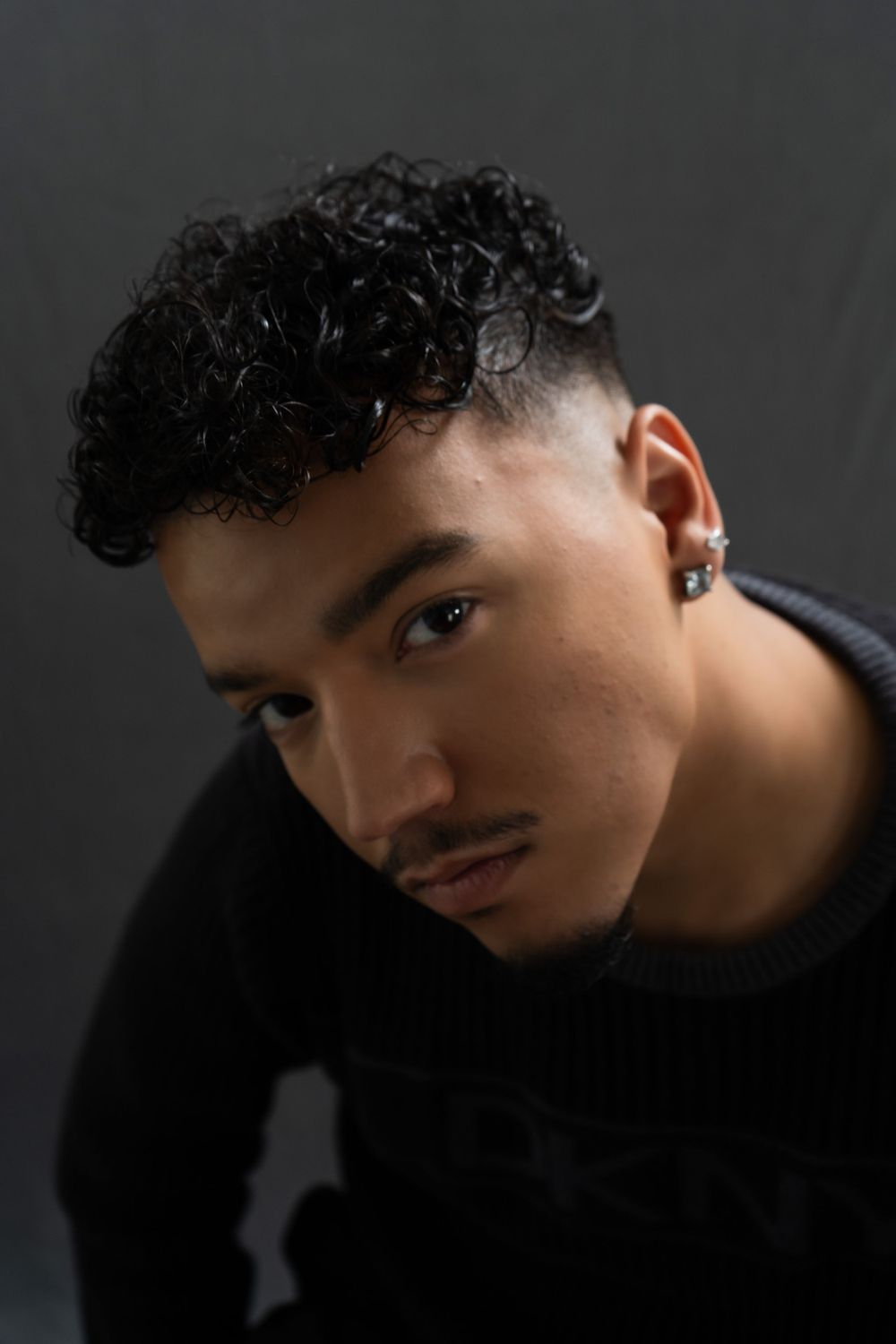 Dramatic studio portrait against dark background with moody lighting.