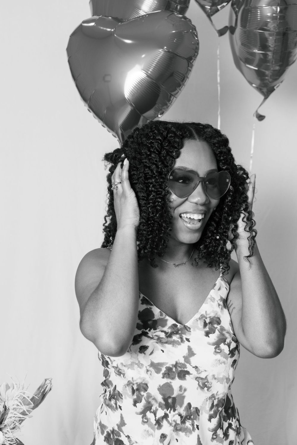 A joyful portrait with heart balloons and a floral dress in black and white.