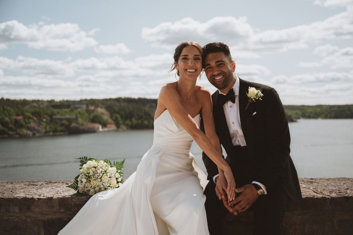 Wedding couple photographed against a scenic coastal landscape on their special day.
