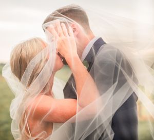 Romantic wedding couple shares intimate moment under flowing veil.