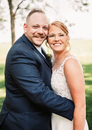 Happy wedding couple in formal attire sharing joyful smiles in outdoor setting.