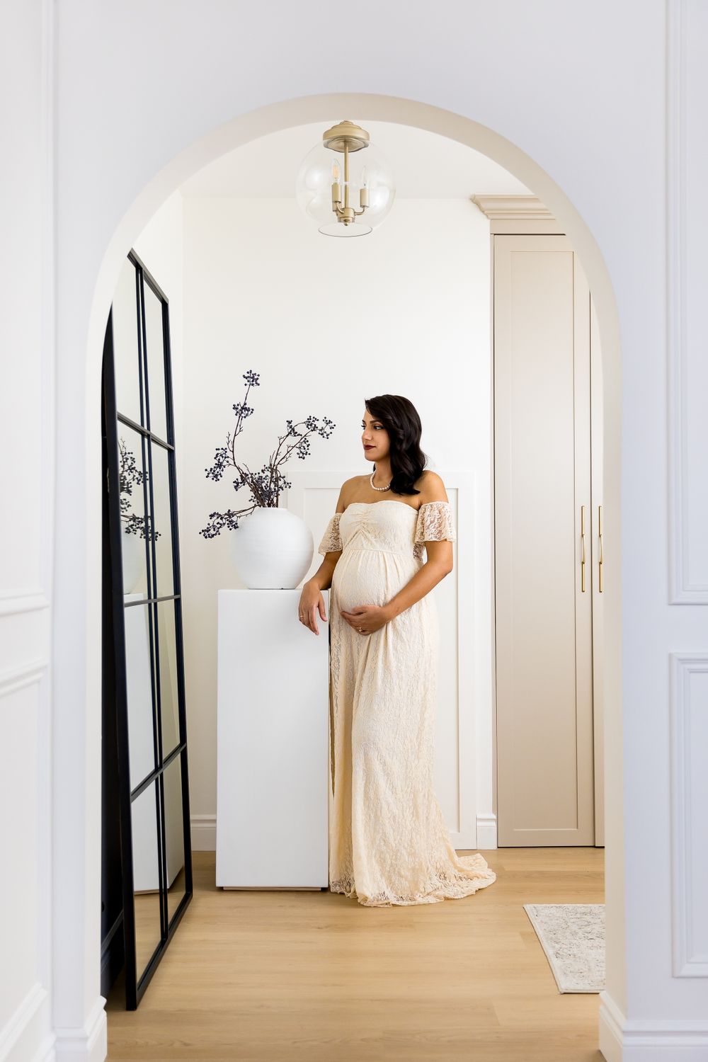 Pregnant women in a maternity gown looking into a mirror in a stunning studio space