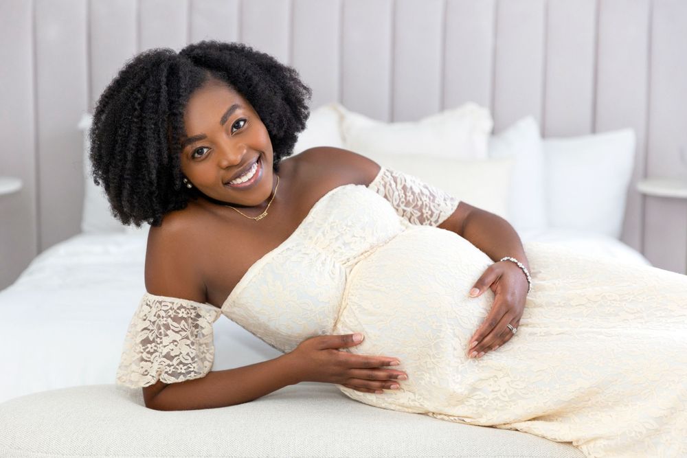 Beautiful Maternity Photography at Mint Room in the white studio with pregnant woman on a styled bed in a dress