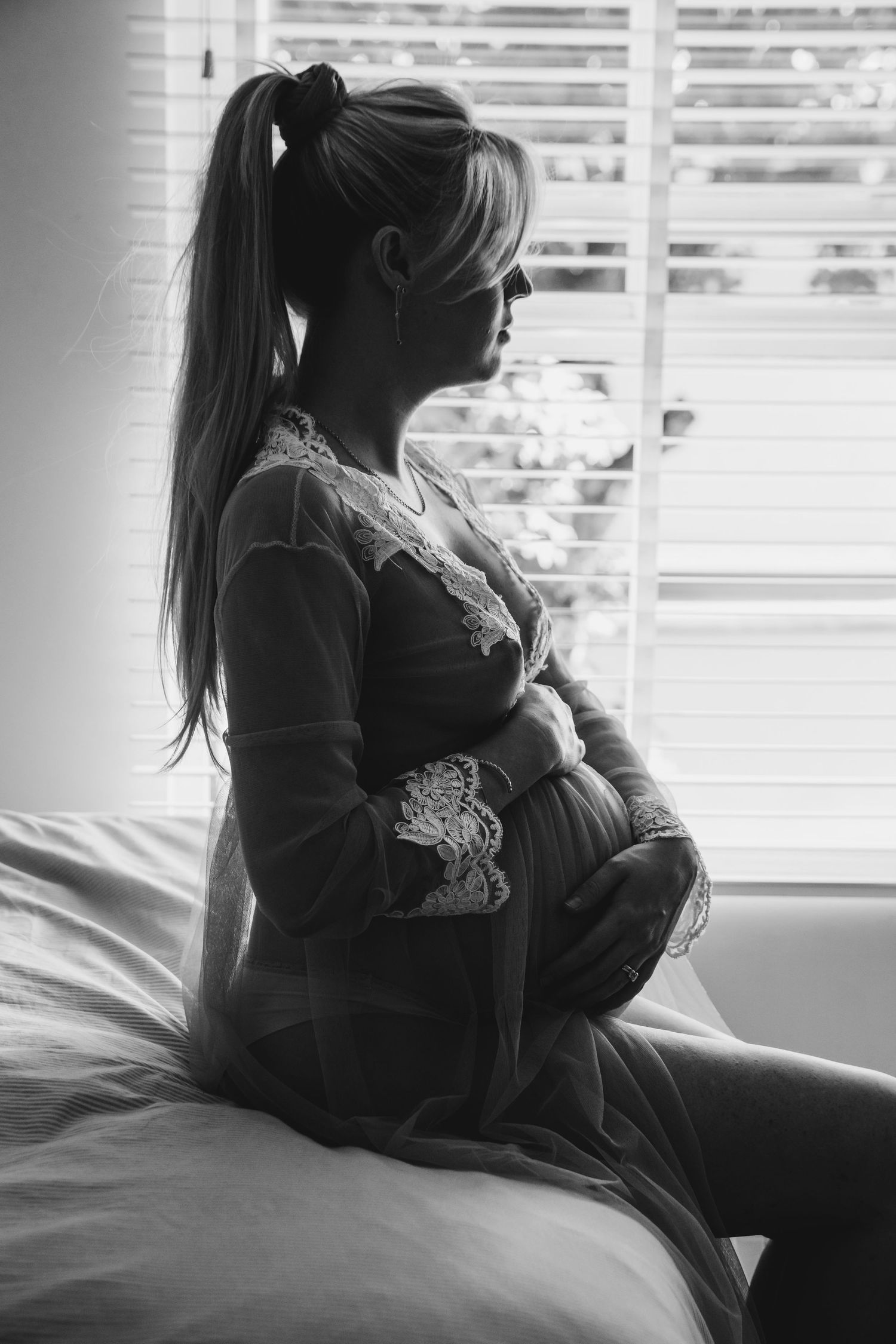 Black and white maternity photo of expectant mother in profile by window, in Stoke Newington.
