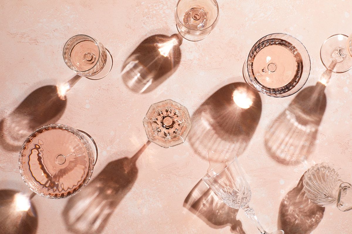 Wine glasses casting elegant shadows in a soft pink light creating a dreamy vintage atmosphere.