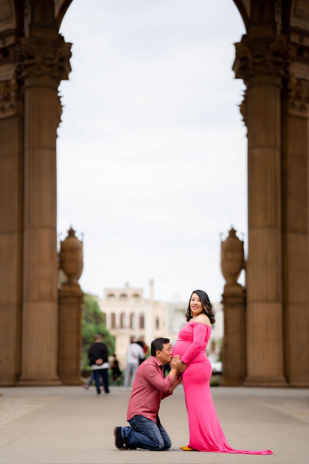 A romantic maternity portrait under an ornate stone archway.