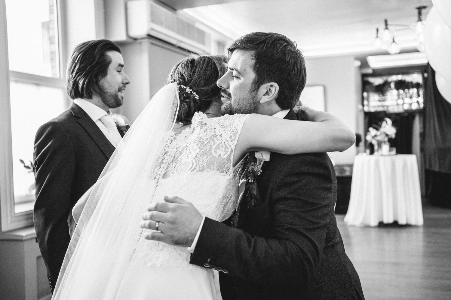 An emotional embrace captured in black and white during a wedding celebration.