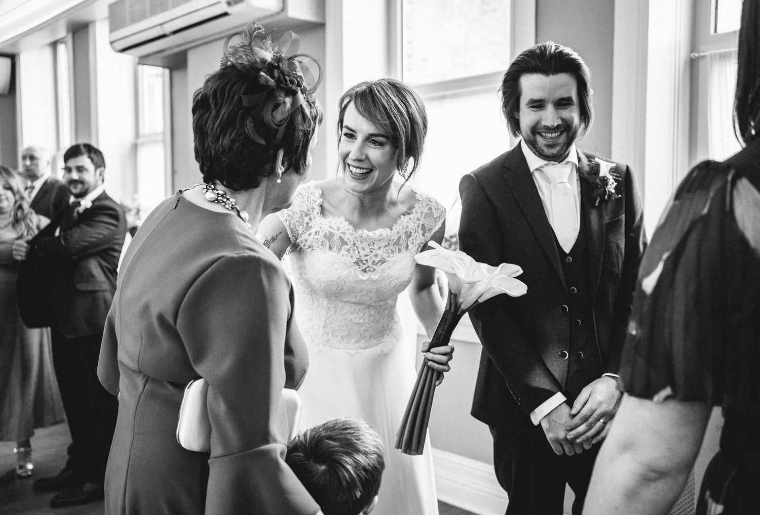 Candid black and white photo of wedding guests sharing a joyful moment during the reception.