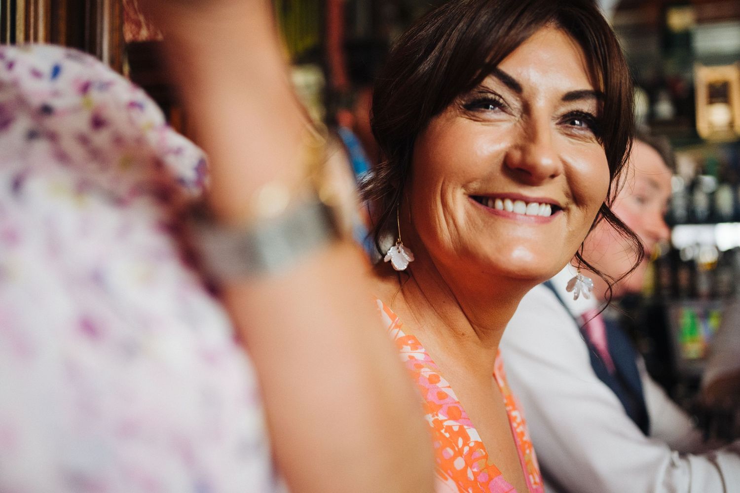 Close-up shot of someone laughing during a celebration wearing coral colored attire.