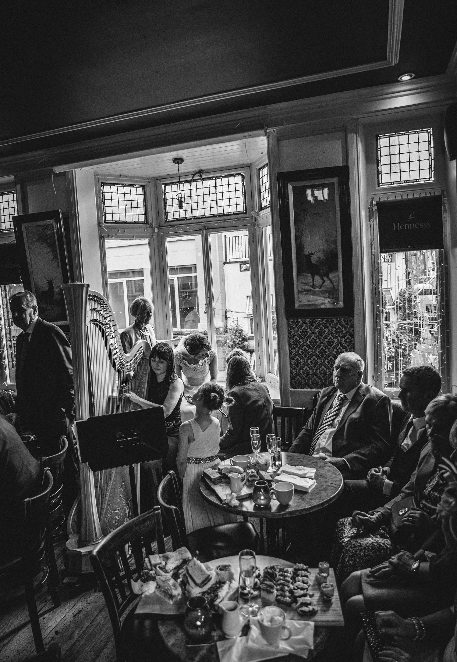 Black and white photo of wedding guests mingling in a vintage-style pub setting.