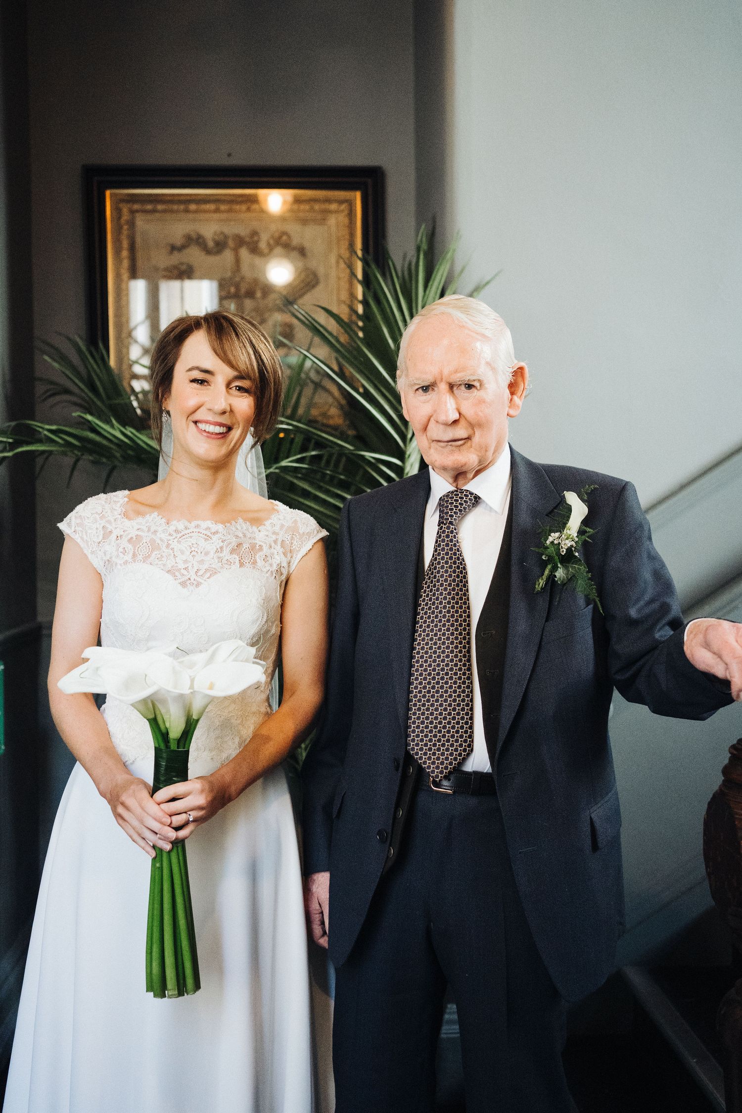 An elegant portrait in front of greenery and a mirror during a formal event.