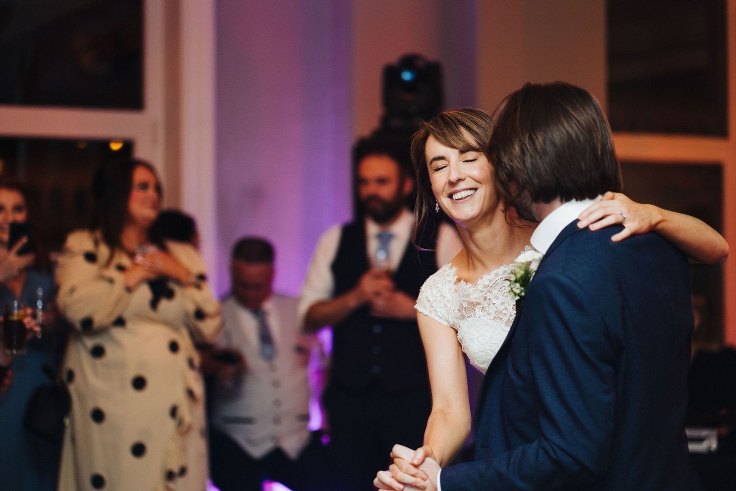 Couple shares a joyful moment during their first dance at an evening wedding reception.