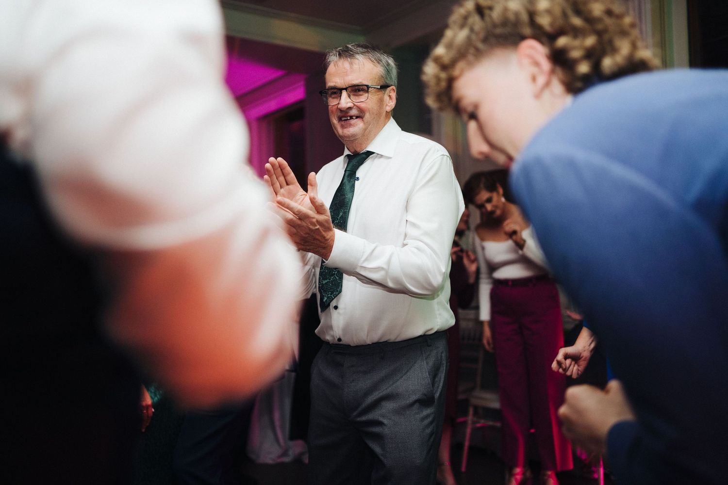 Wedding guests celebrating on a dance floor with festive lighting.