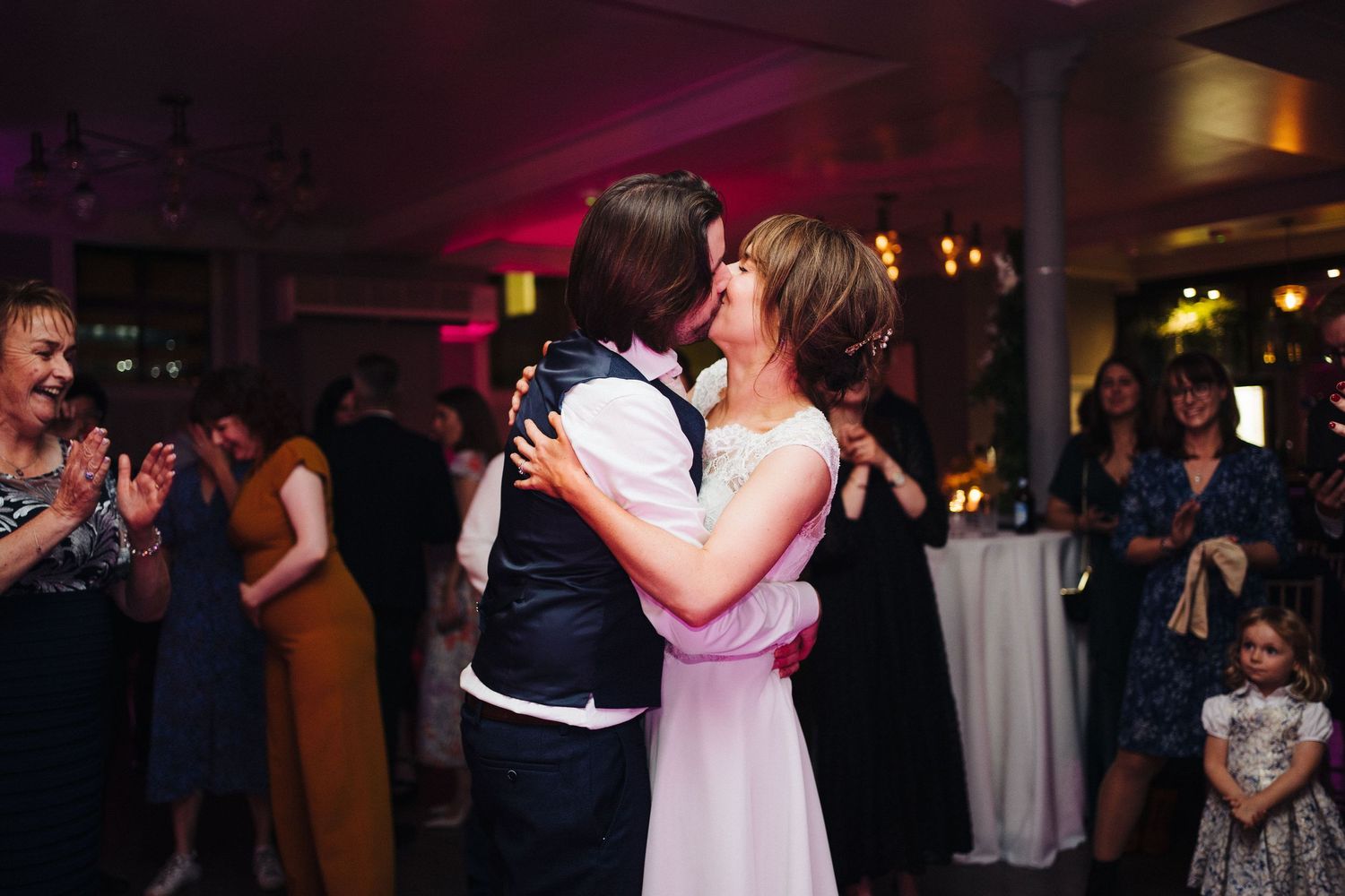 Couple sharing an intimate dance moment while guests watch from the background.