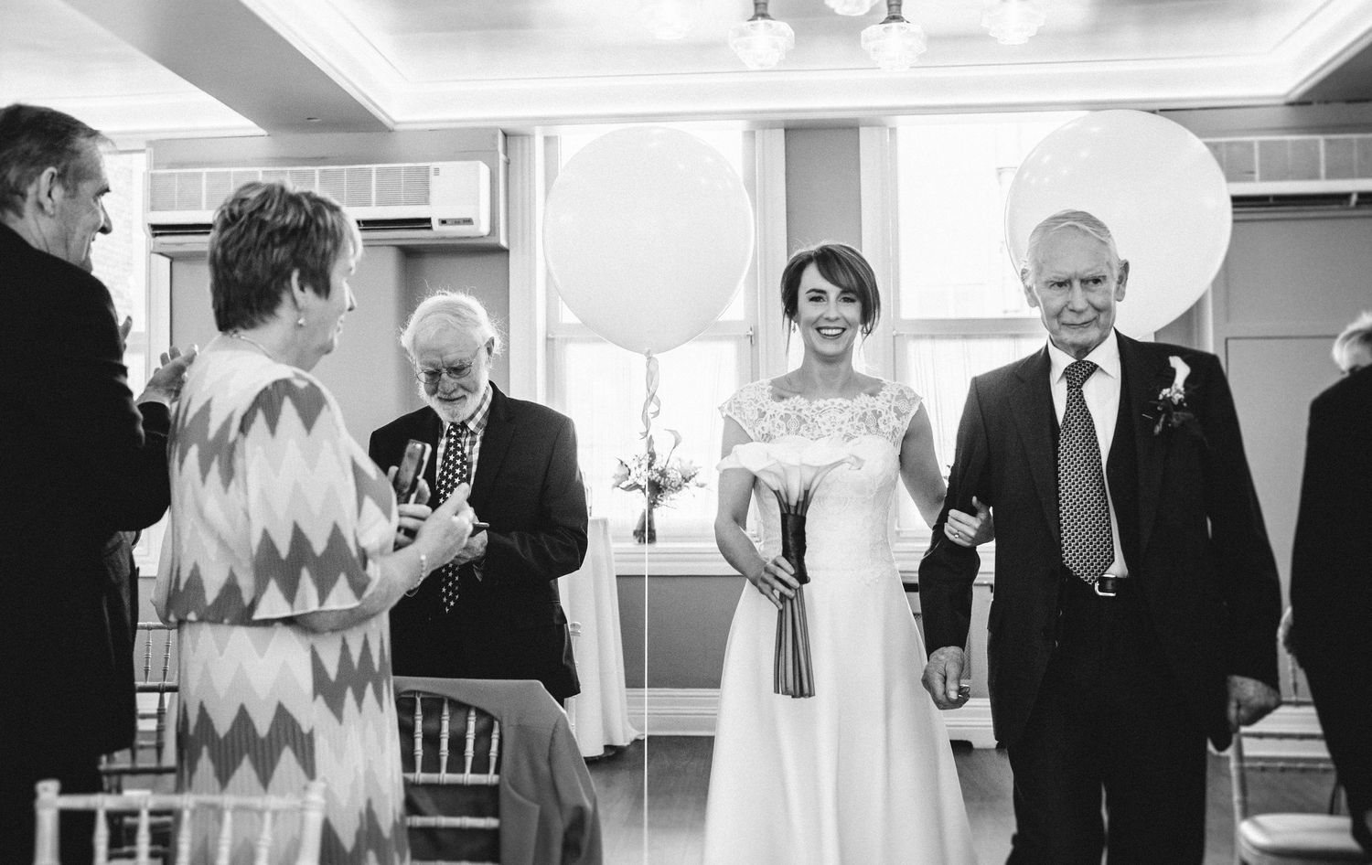 A formal celebration in a room decorated with white balloons and elegant furnishings.