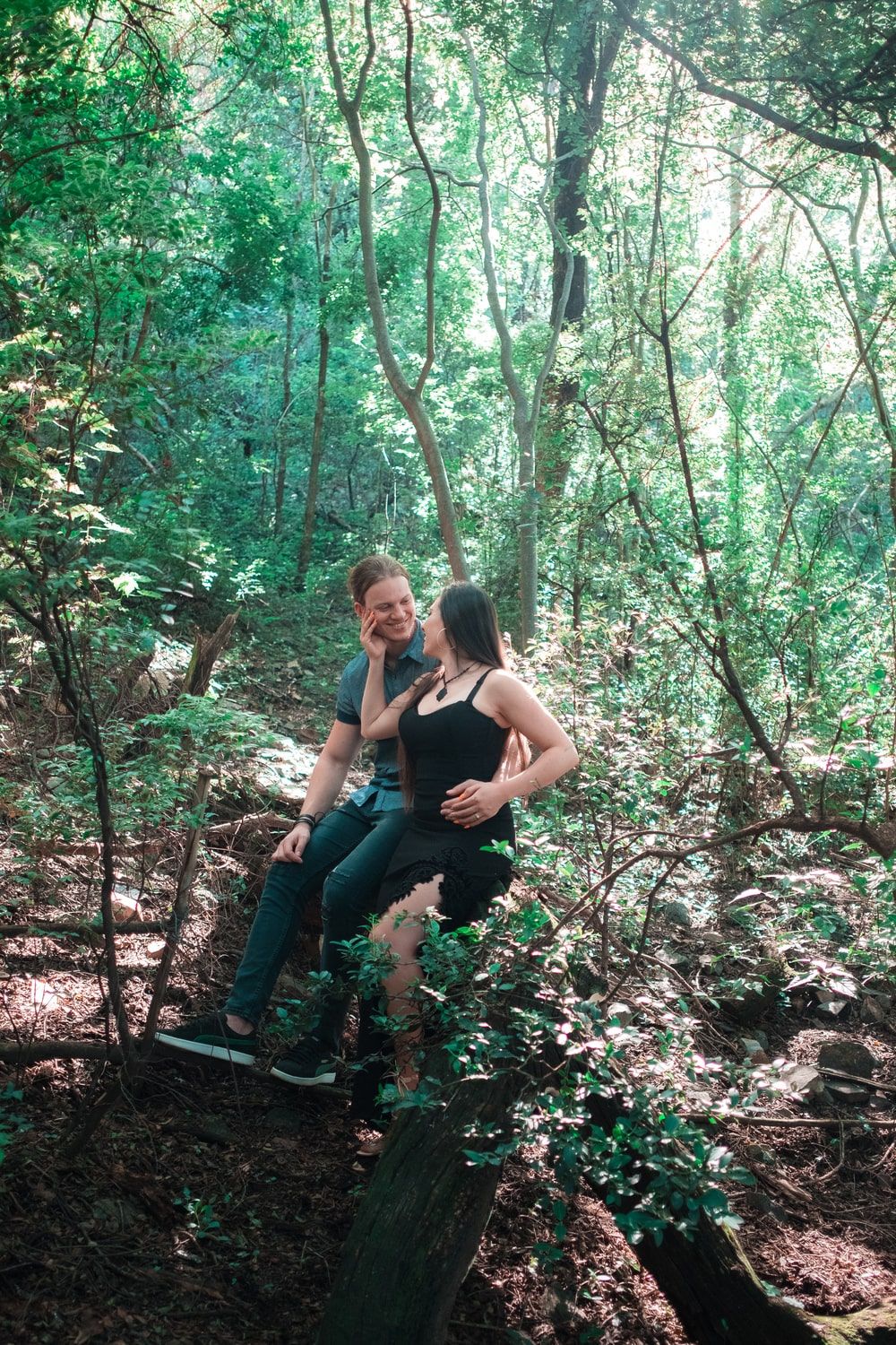 Couple sit on fallen tree in green forest at the Sisulu Botanical Gardens