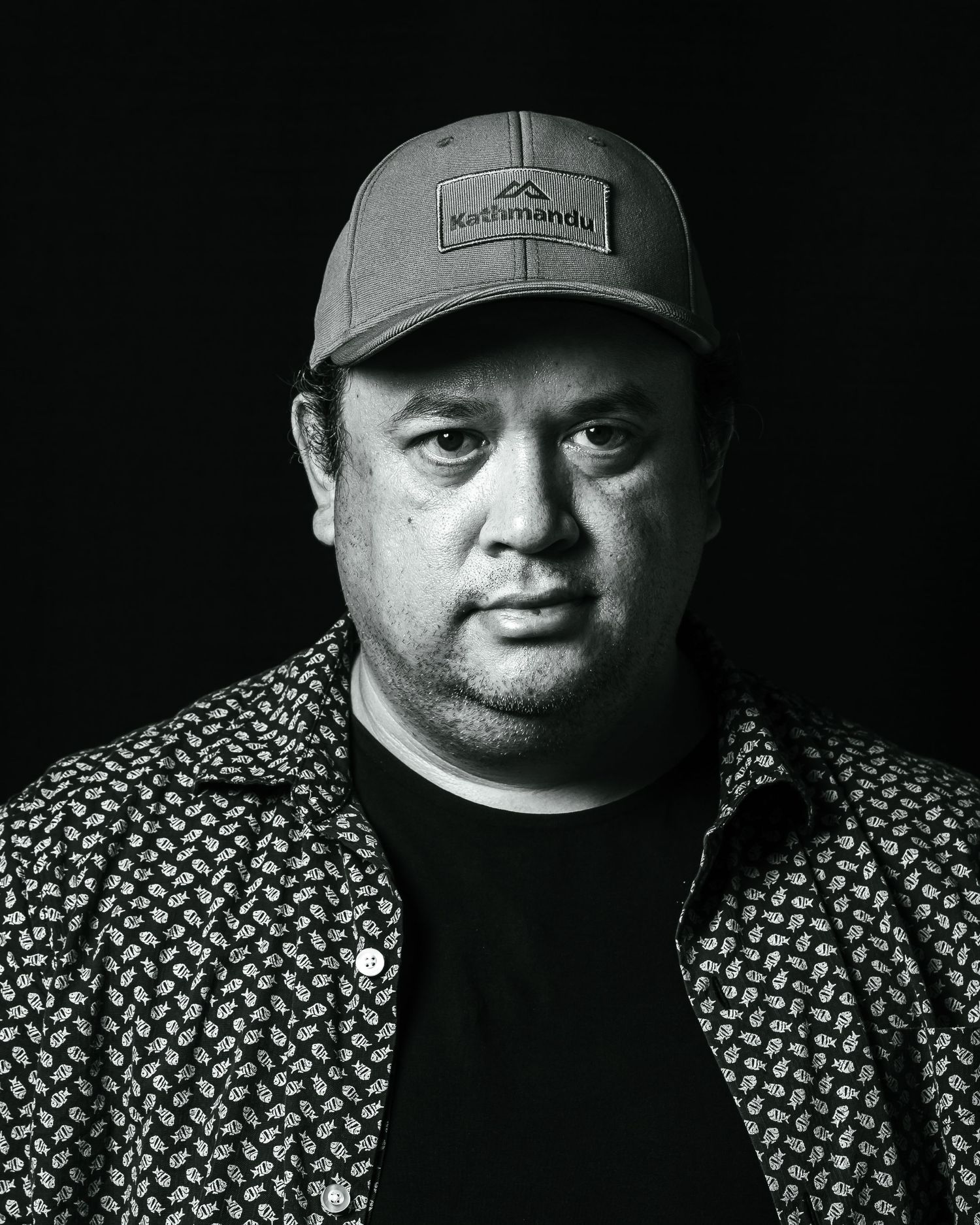 Black and white portrait with dramatic lighting and textured clothing.